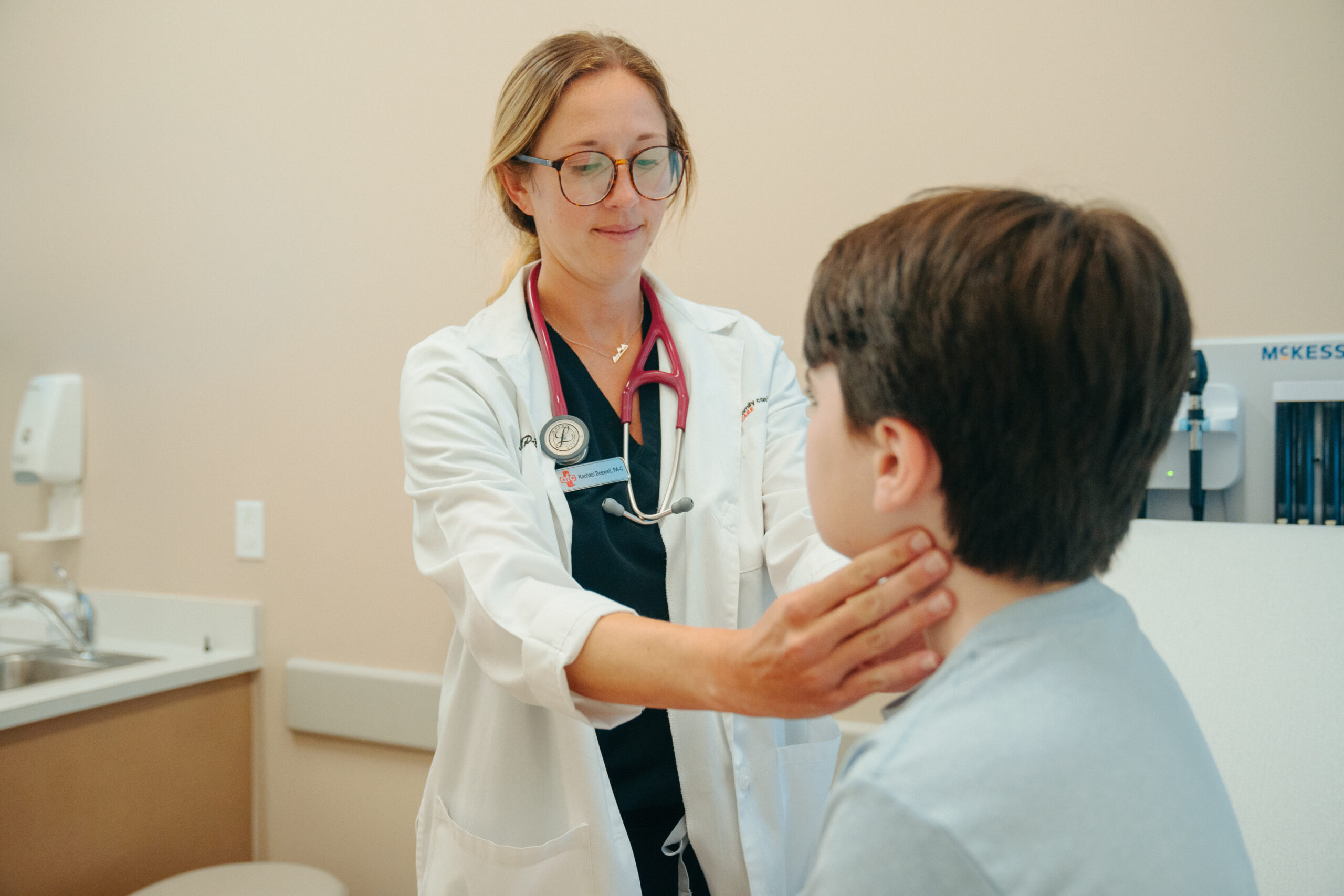 Female AFC provider examines young patient's lymph nodes for RSV